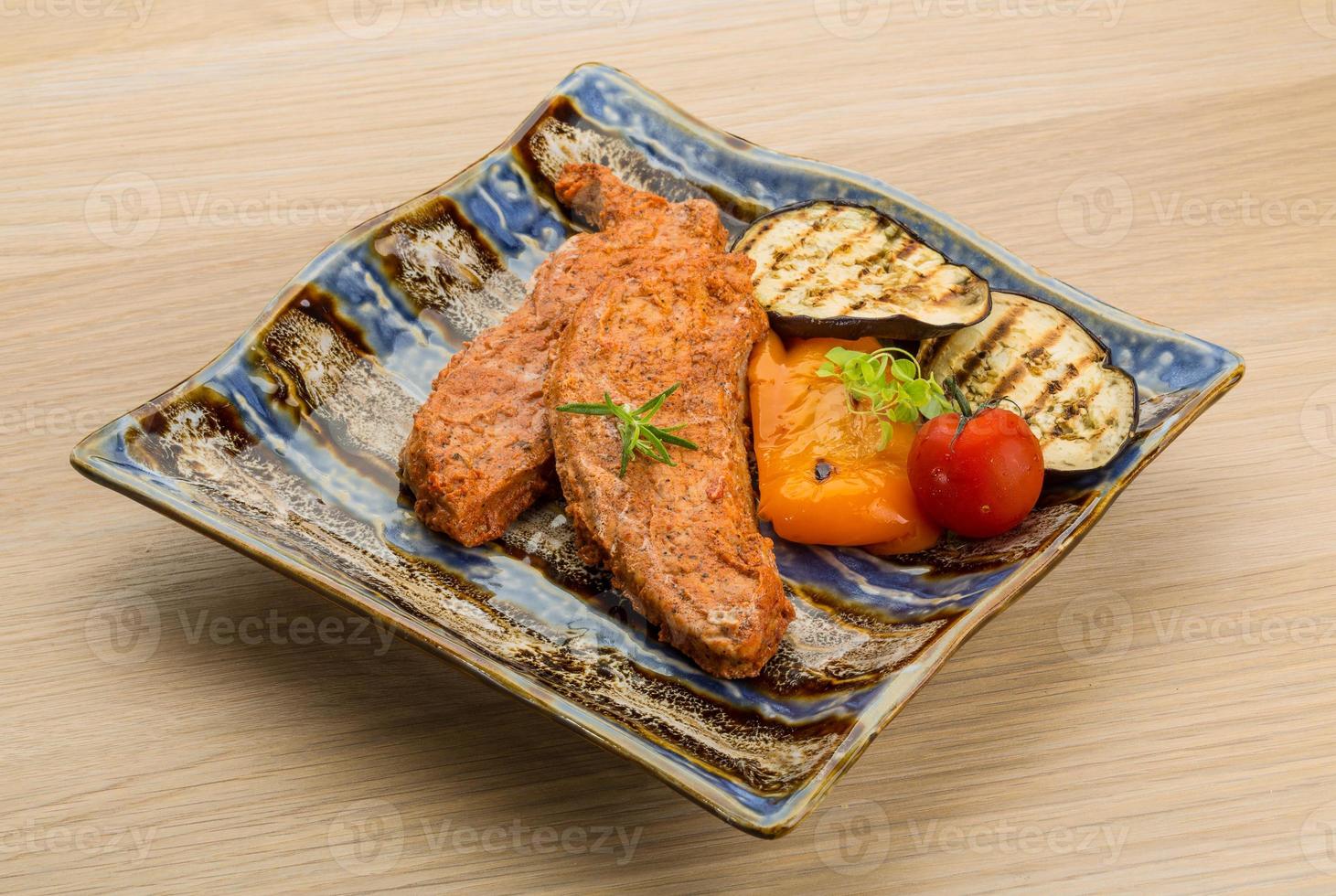 Schweinesteak auf dem Teller und Holzhintergrund foto