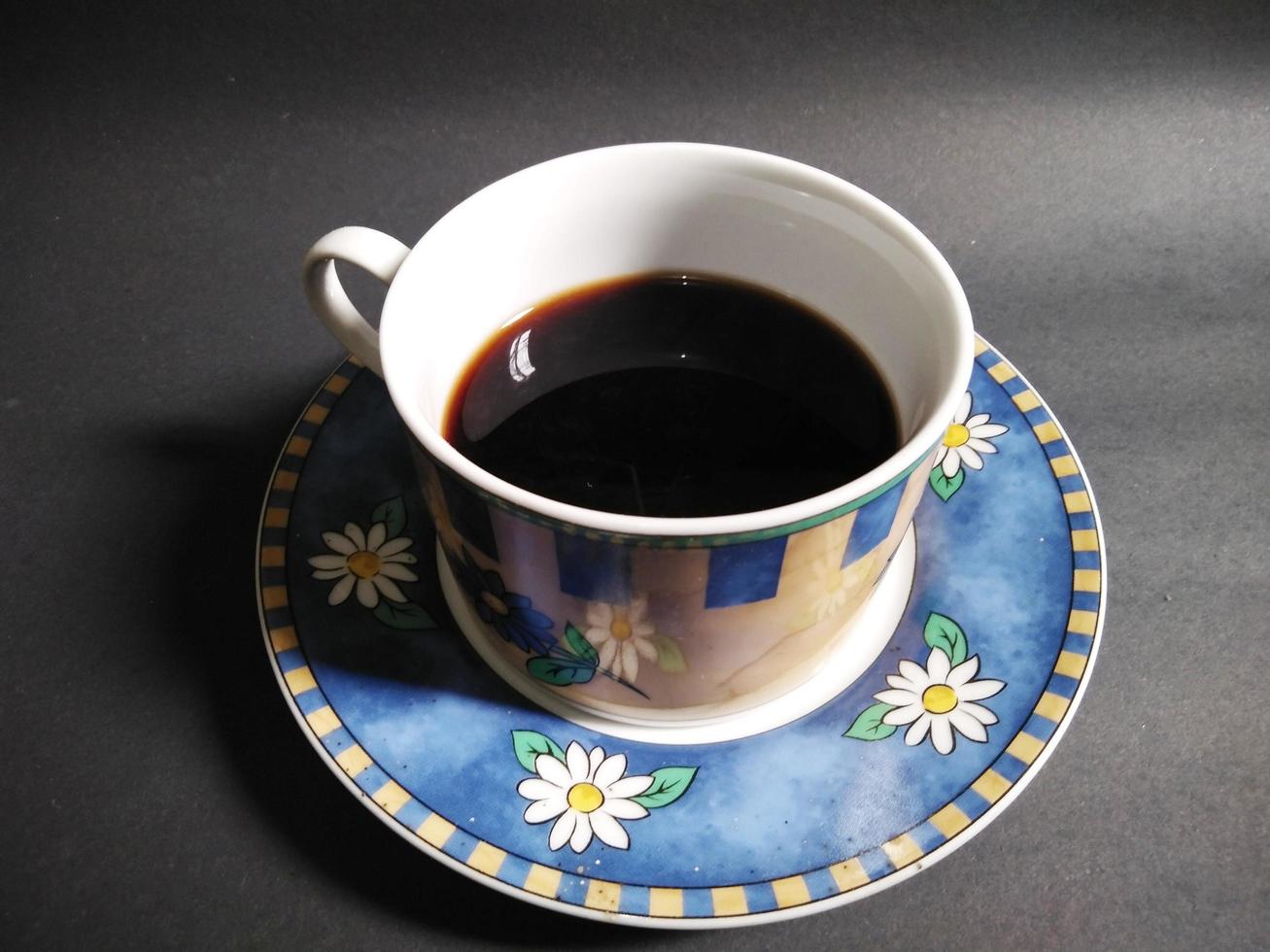 Blumenmuster der Kaffeetasse auf schwarzem Hintergrund foto