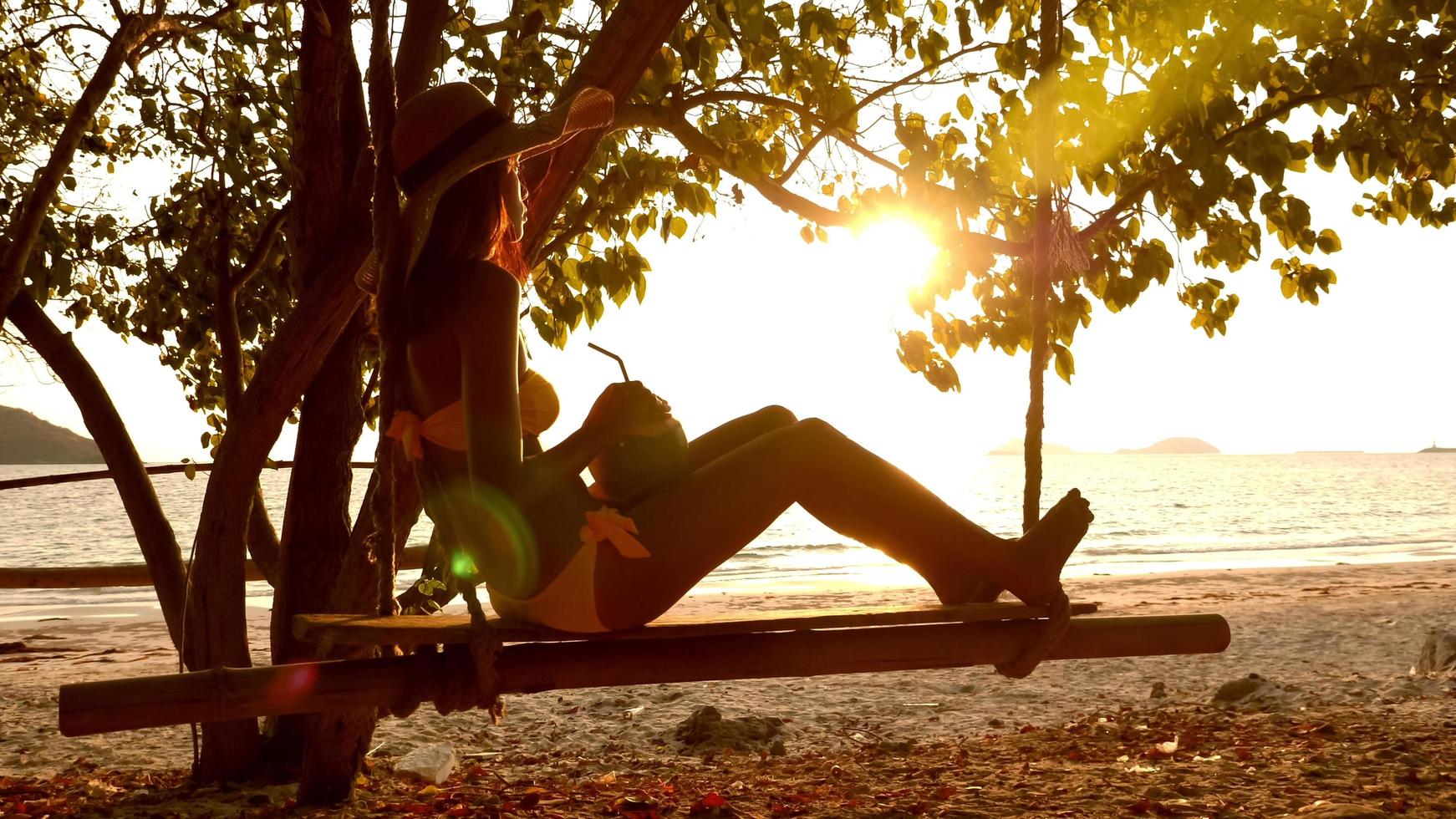 sexy frau in gelber badebekleidung, die auf einer schaukel am strand sitzt. foto