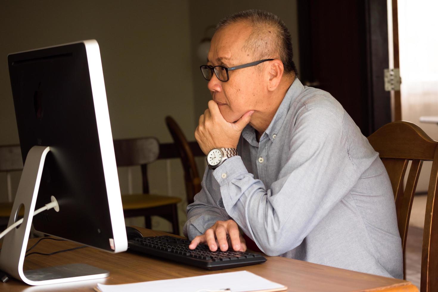 asiatischer geschäftsmann sitzt und schaut auf computer im büroraum. foto