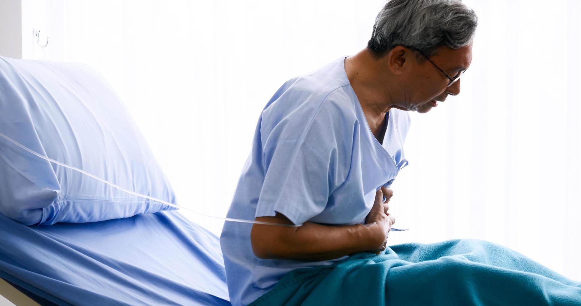 männlicher patient mit brustschmerzen auf dem krankenbett im krankenhauszimmer. foto
