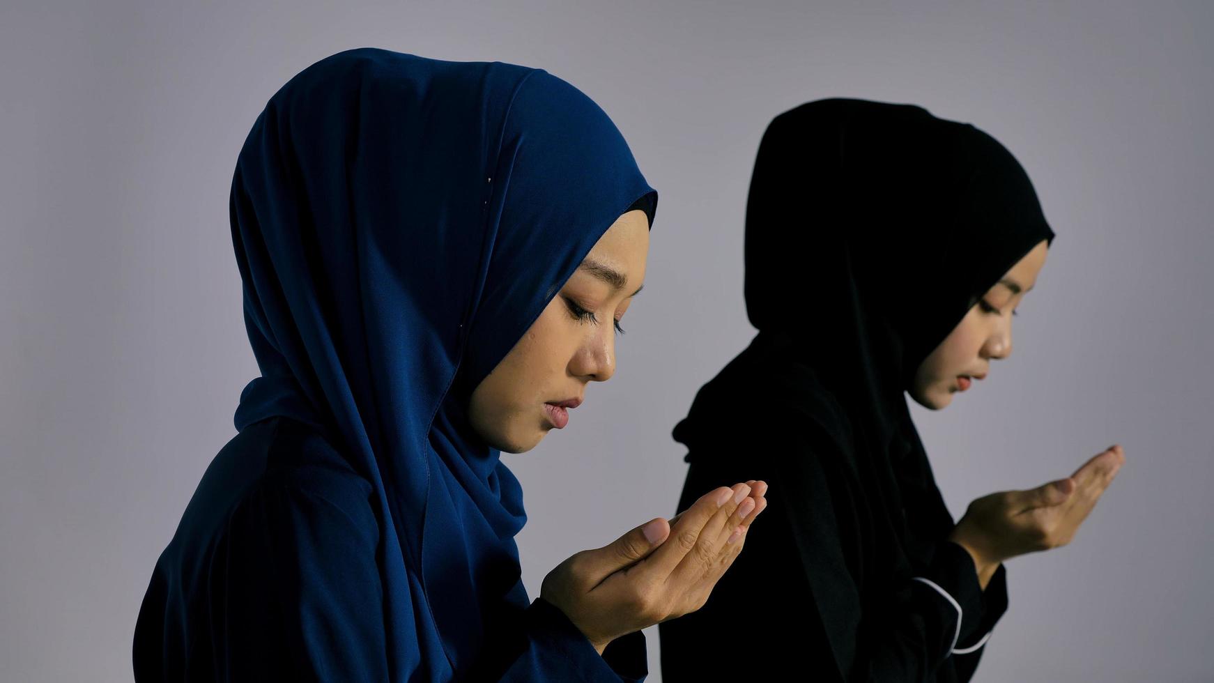 zwei asiatische muslimische junge frauen im traditionellen hijab beten, verherrlichen allah und praktizieren den islamischen glauben in der moschee. foto