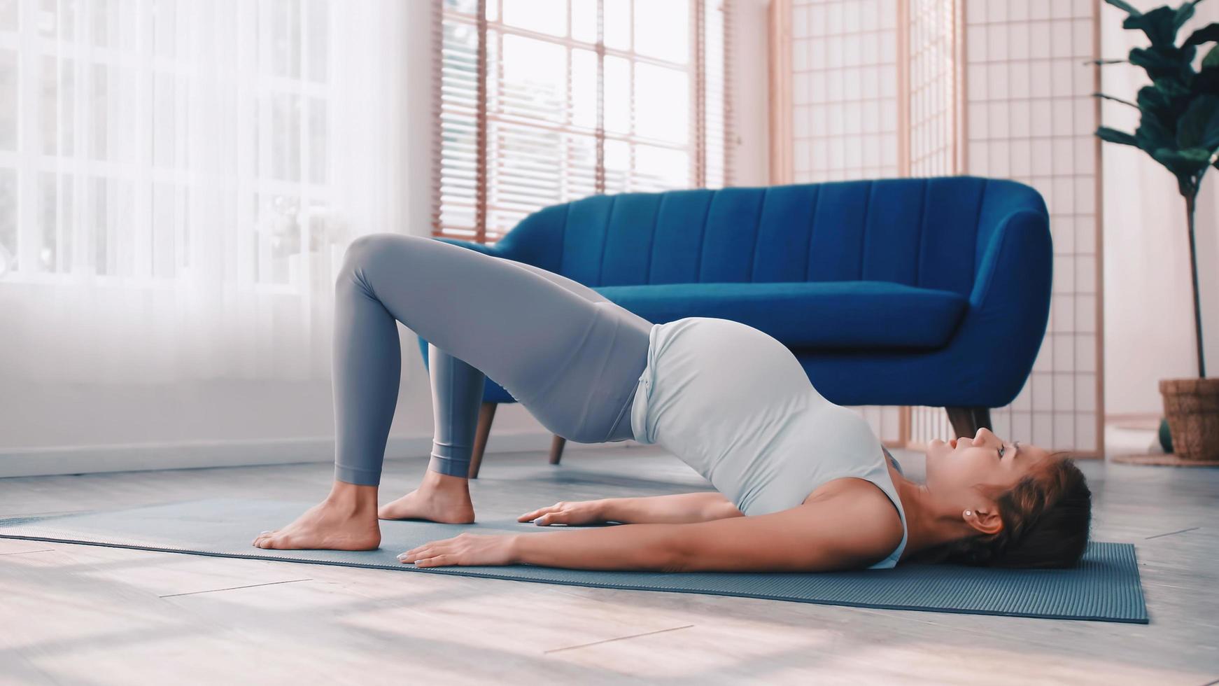 asiatische schwangere frau, die zu hause yoga-übungen macht. foto