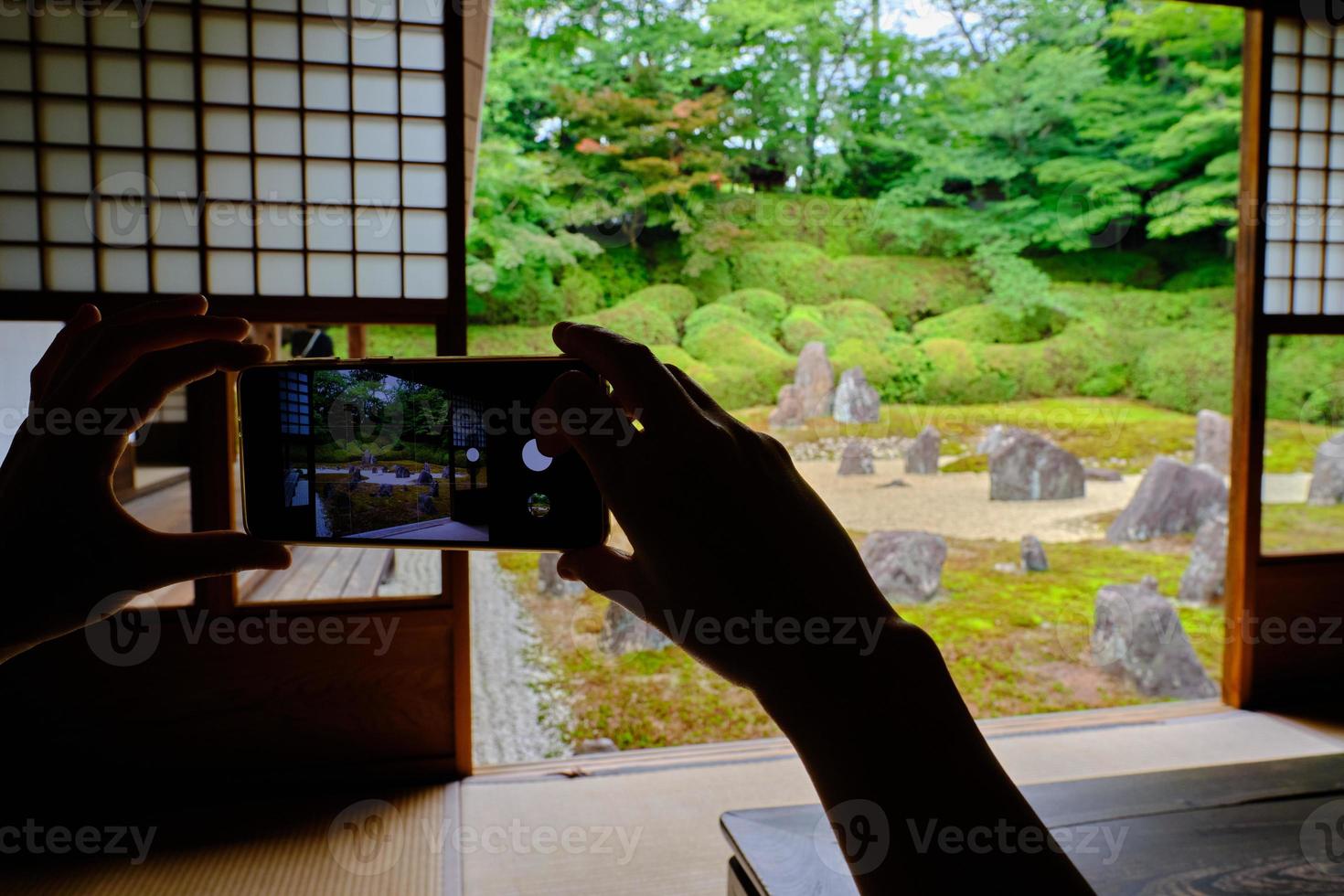 Hände fotografieren einen japanischen Steingarten mit einem Smartphone foto