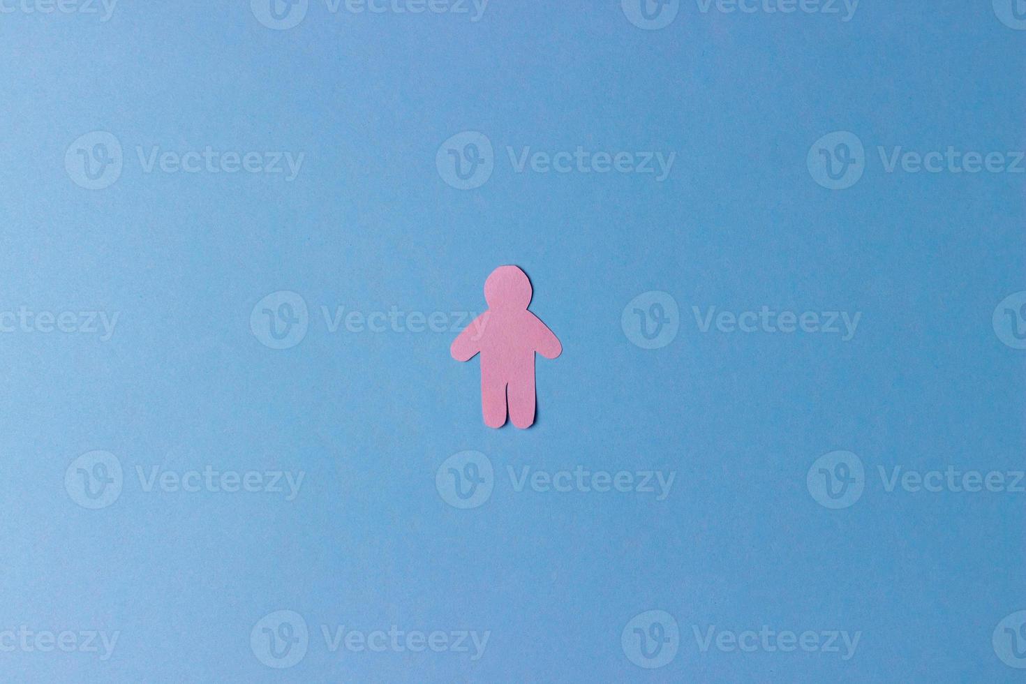 die Silhouette eines Mannes, geschnitzt aus rosafarbenem Papier auf blauem Grund foto