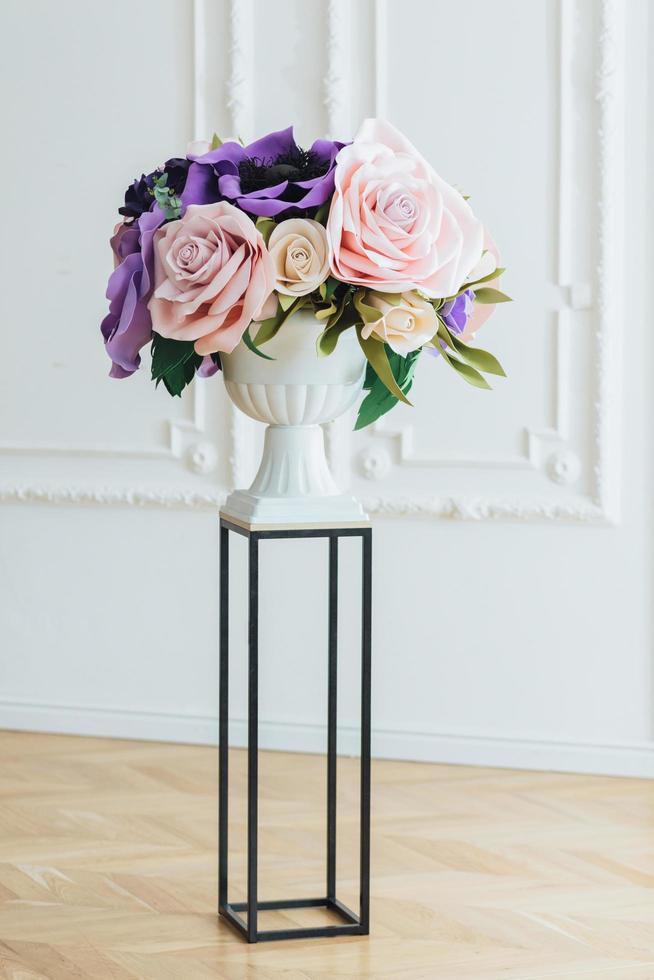 wunderbarer Blumenstrauß aus rosa Rosen und lila Mohn in eleganter weißer Vase auf Ständer vor weißem Hintergrund. festliche Veranstaltung. Dekoration mit Blumen foto