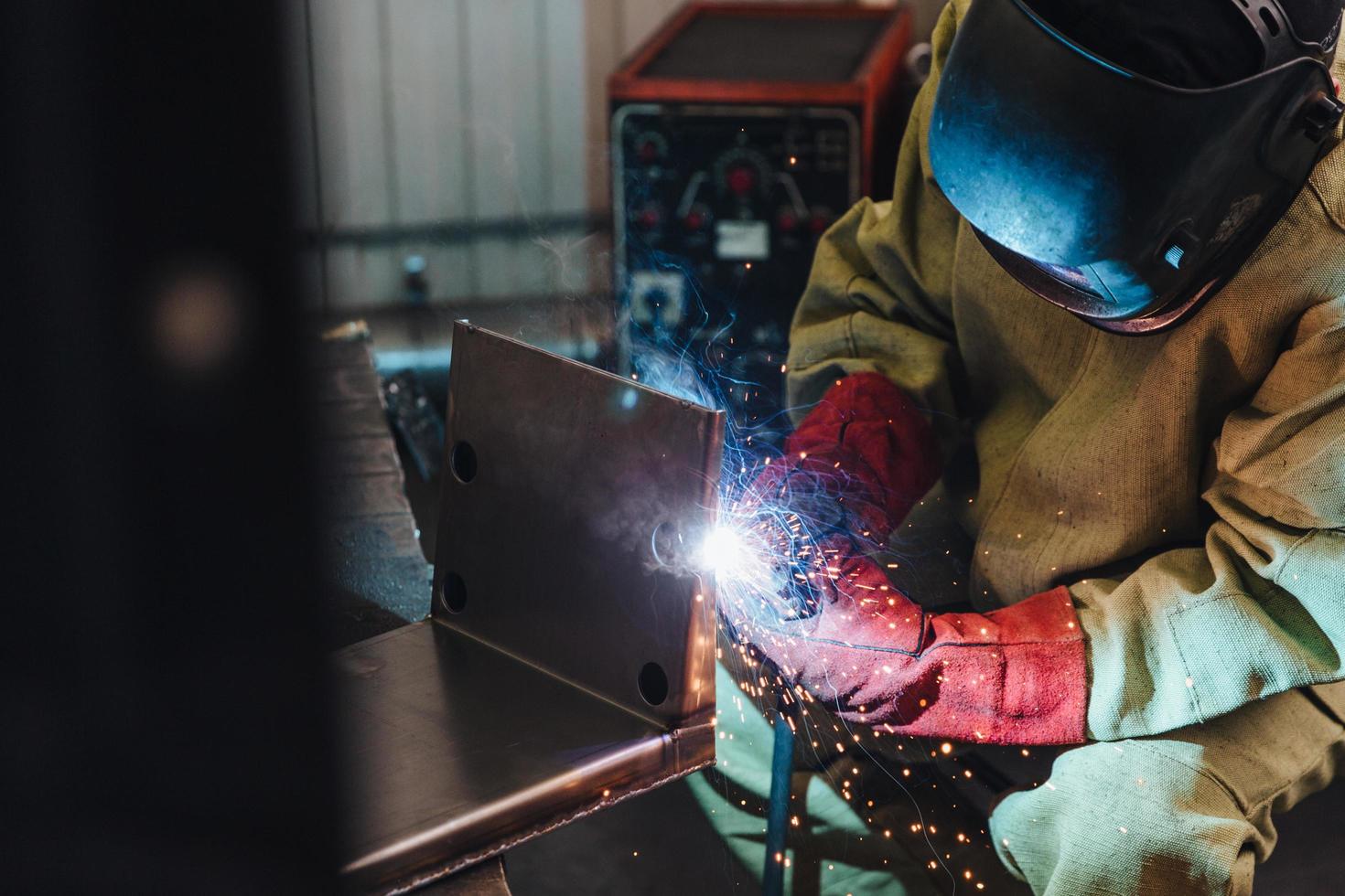 Schweißkonzept. industriearbeiter oder schweißer tragen schutzmaske und handschuhe errichten technischen stahl in der fabrik. Arbeiter schweißt Metall. Mann repariert Details im Autoservice. Stahlarbeiter foto