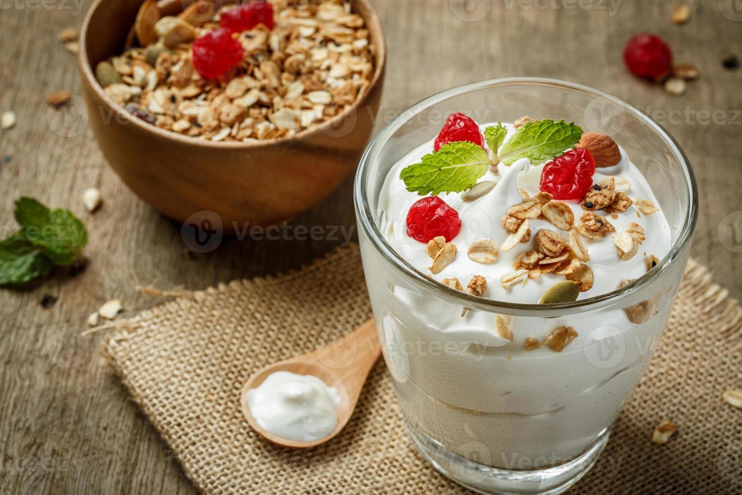 griechischer joghurt in einem glas mit löffeln auf holzhintergrund foto