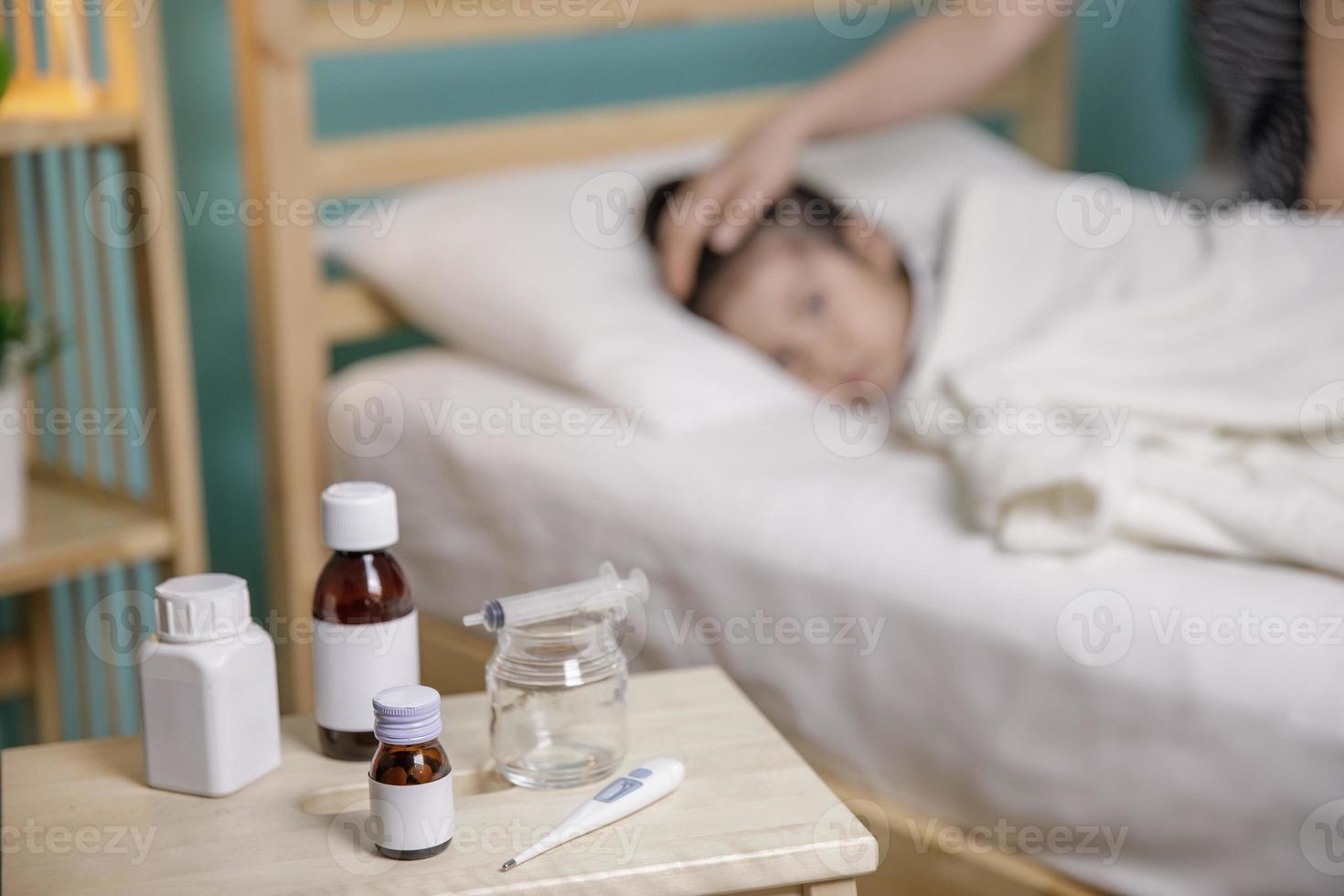 Das kleine Mädchen war krank und schlief im Bett. mutter kümmert sich und legt ihrer tochter eine decke an foto