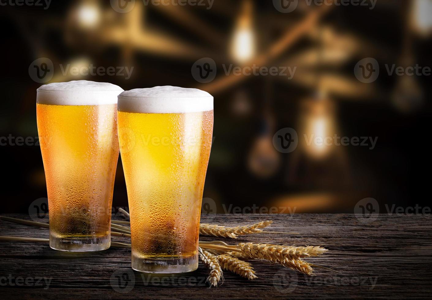 Gläser helles Bier mit Gerste an der Bar. zwei Glas Bier mit Weizen auf Holztisch foto