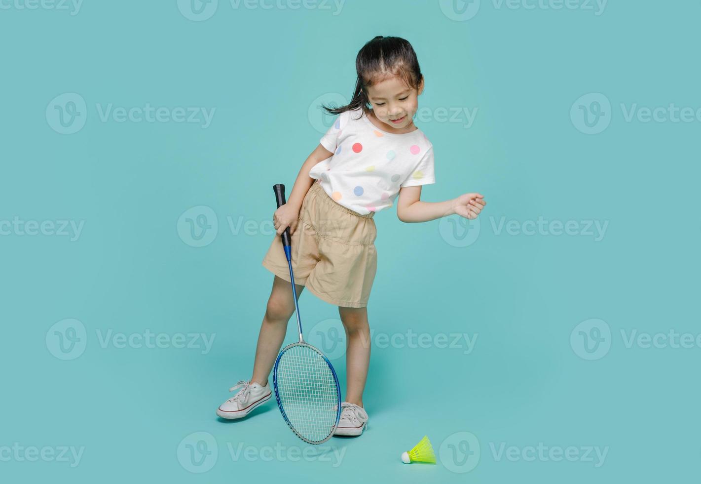 Fröhliches asiatisches Kind, das Badminton spielt, Studioaufnahme isoliert auf buntem blauem Hintergrund foto