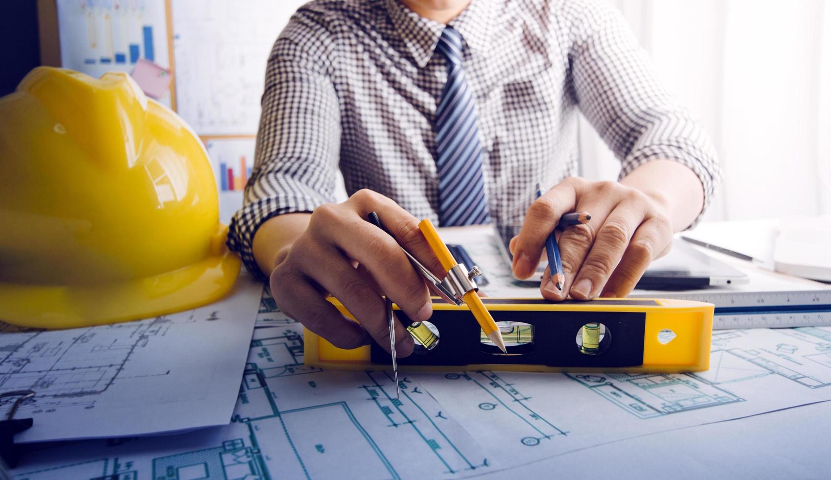 Zwei Kollegen diskutieren über Datenverarbeitung und Tablet, Laptop mit einem Architekturprojekt auf der Baustelle am Schreibtisch im Büro foto