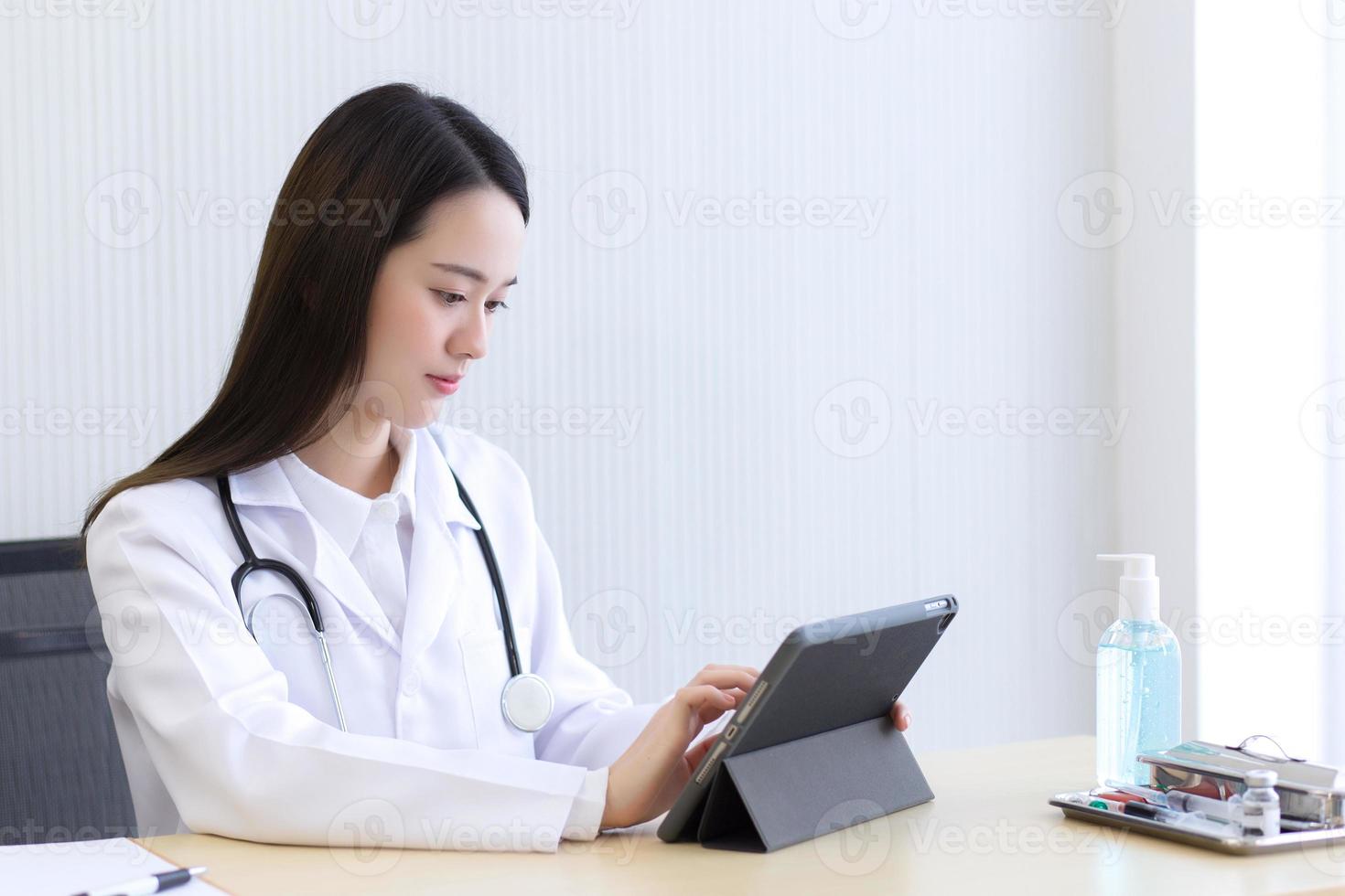 Coronavirus-Schutz, neues Normal- und Gesundheitskonzept. seriöser professioneller Arzt mit weißem Kittel und Stethoskop, der ein modernes Touchscreen-Gerät mit digitalem Tablet-Computer bei der Arbeit hält. foto