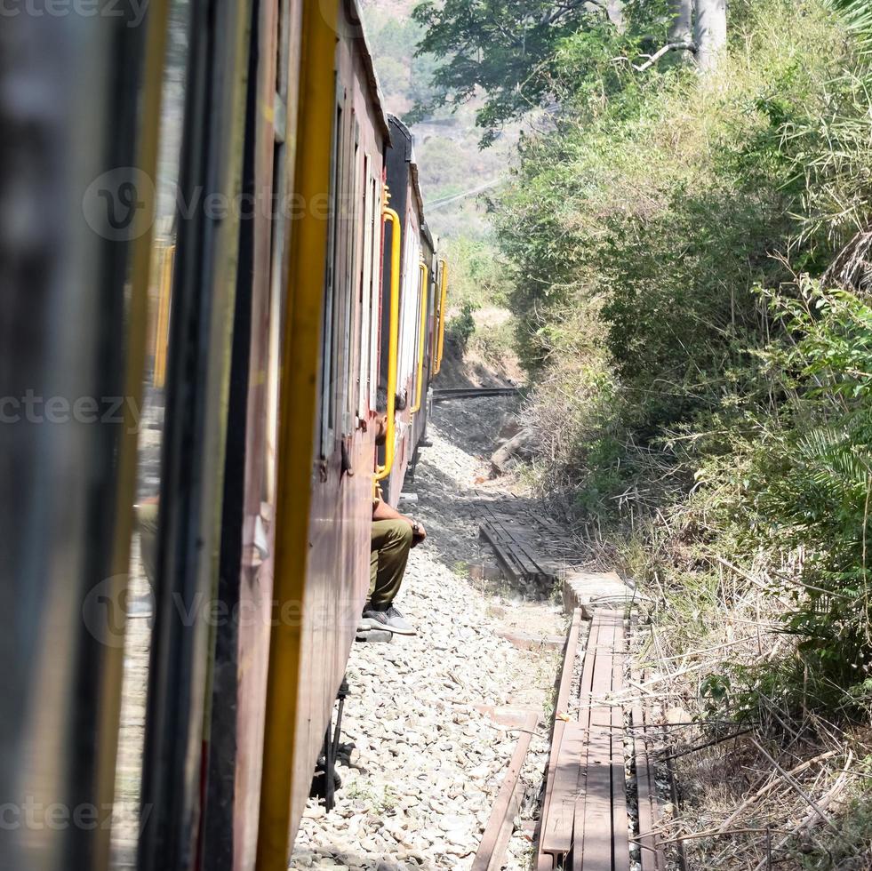 Spielzeugeisenbahn, die sich auf Berghängen bewegt, schöne Aussicht, ein Seitenberg, ein Seitental, das sich auf der Eisenbahn zum Hügel bewegt, inmitten grüner Naturwälder. spielzeugeisenbahn von kalka nach shimla in indien, indischer zug foto