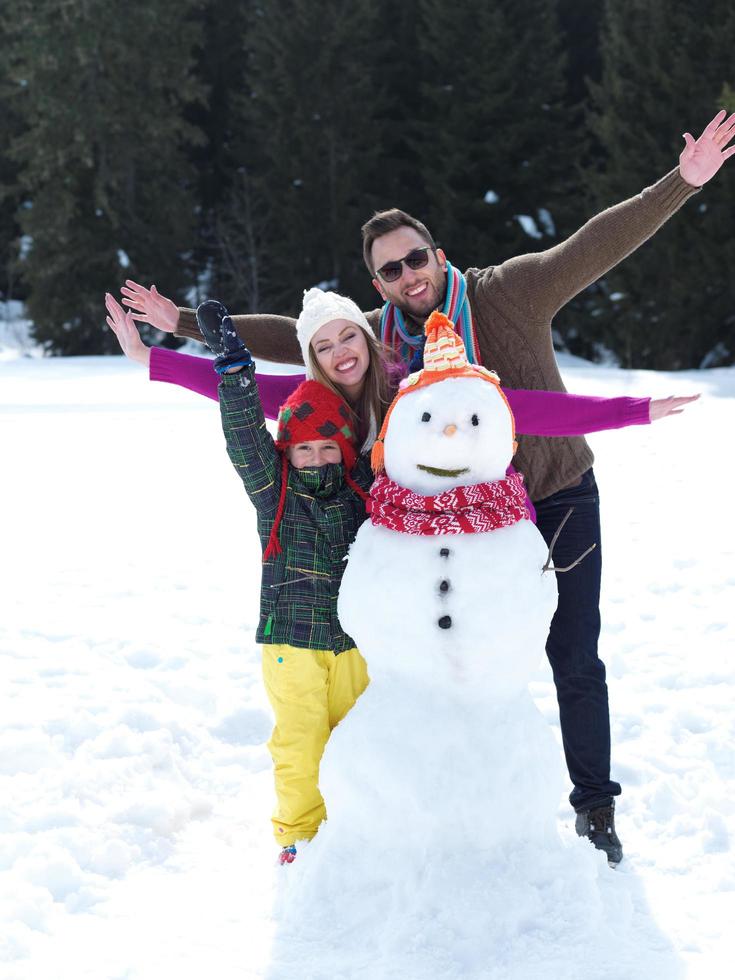 glückliche Familie, die Schneemann macht foto