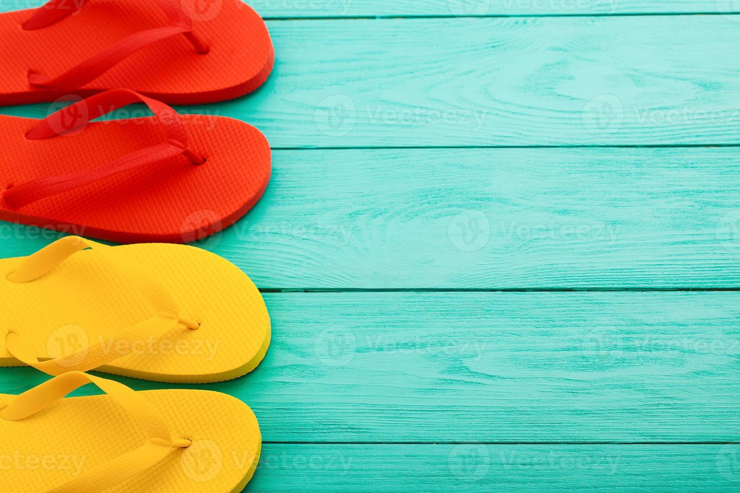 Bunte Flip-Flops auf blauem Holzhintergrund mit Kopierraum. Ansicht von oben foto