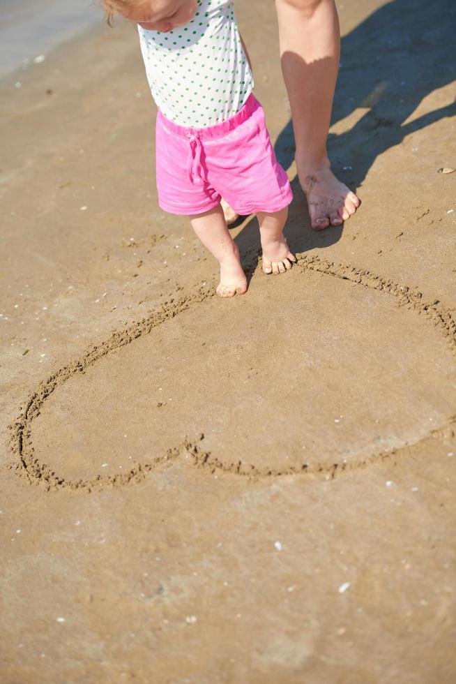 Mama und Baby am Strand haben Spaß foto