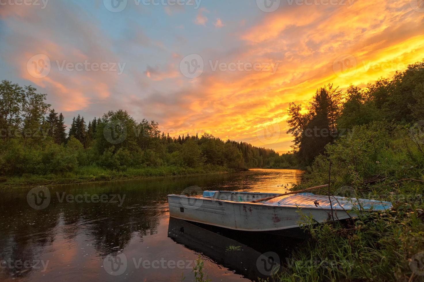 heller dramatischer Sonnenuntergang über Fluss mit Boot im Vordergrund foto