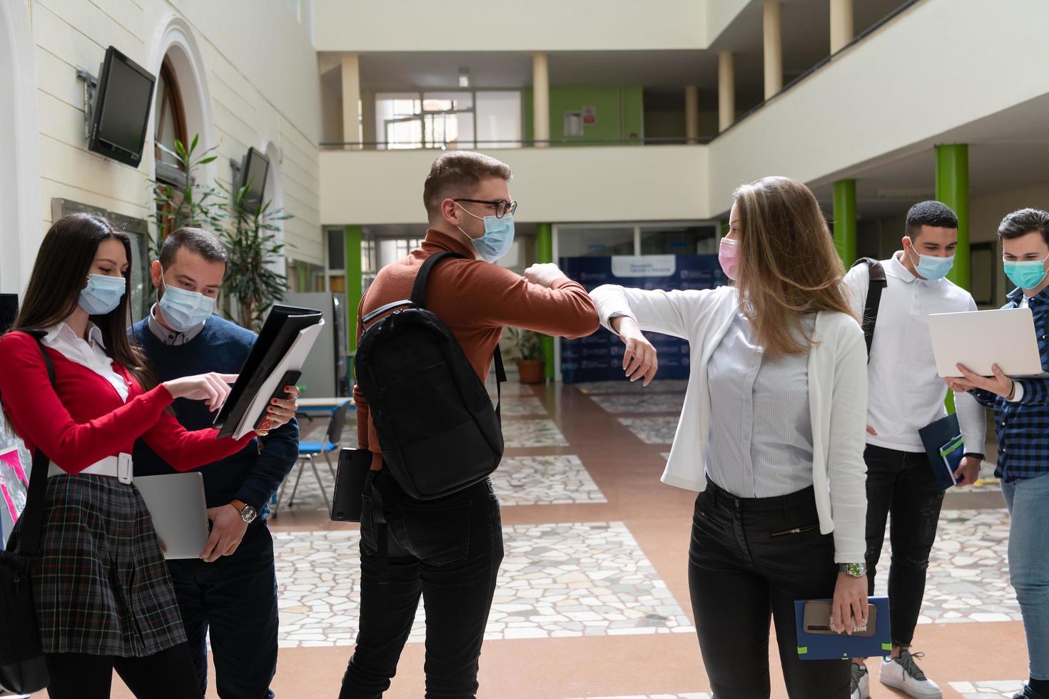 studenten begrüßen den neuen normalen coronavirus-händedruck und ellbogenstoß foto