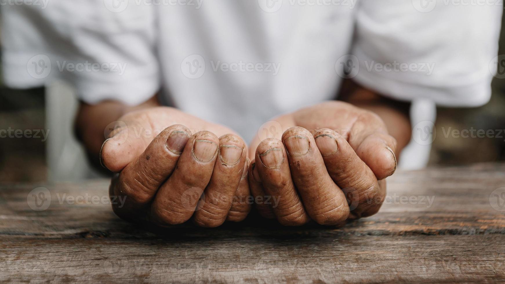 Hände eines alten Mannes auf dem Holztisch. im Sonnenlicht foto