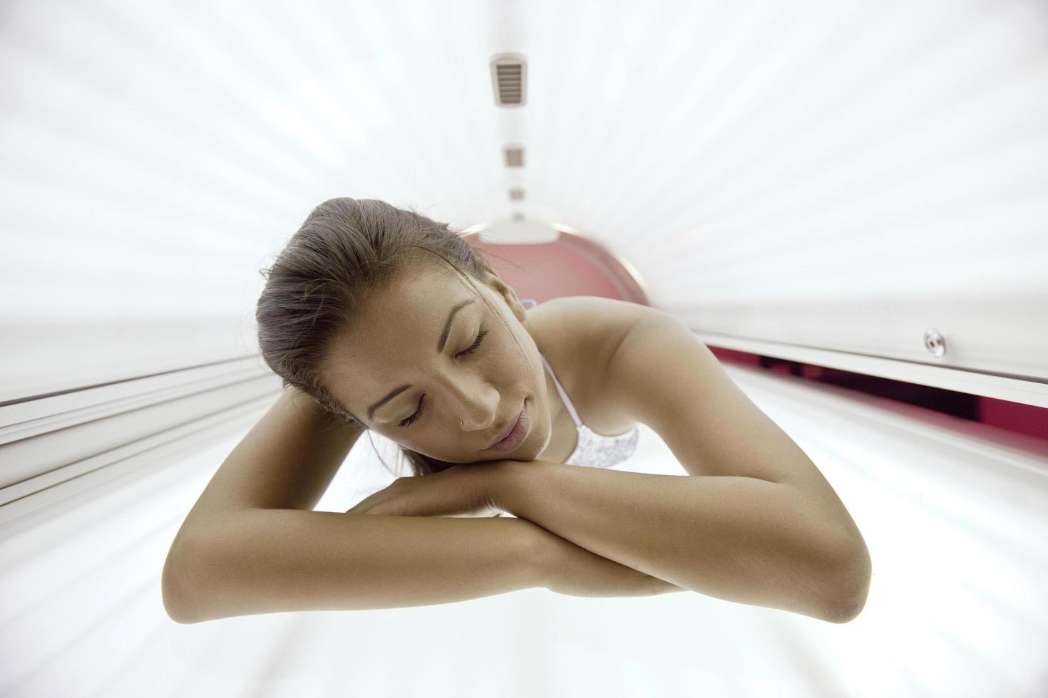 schöne junge Frau im Solarium bräunen foto