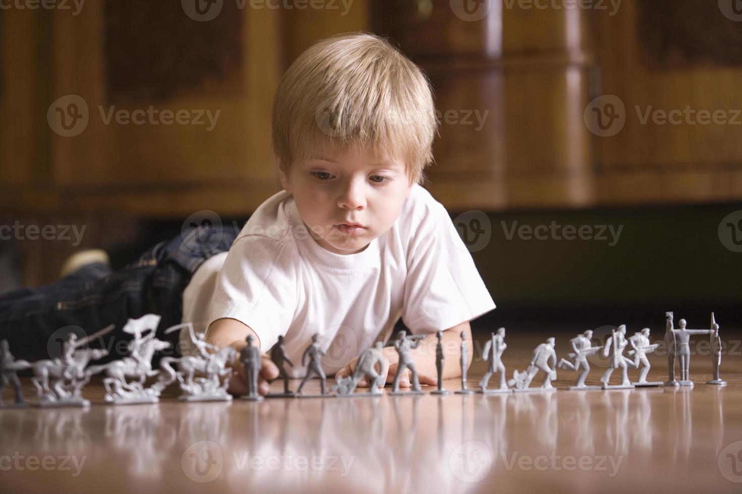 Junge spielt mit Spielzeugsoldaten auf dem Boden foto
