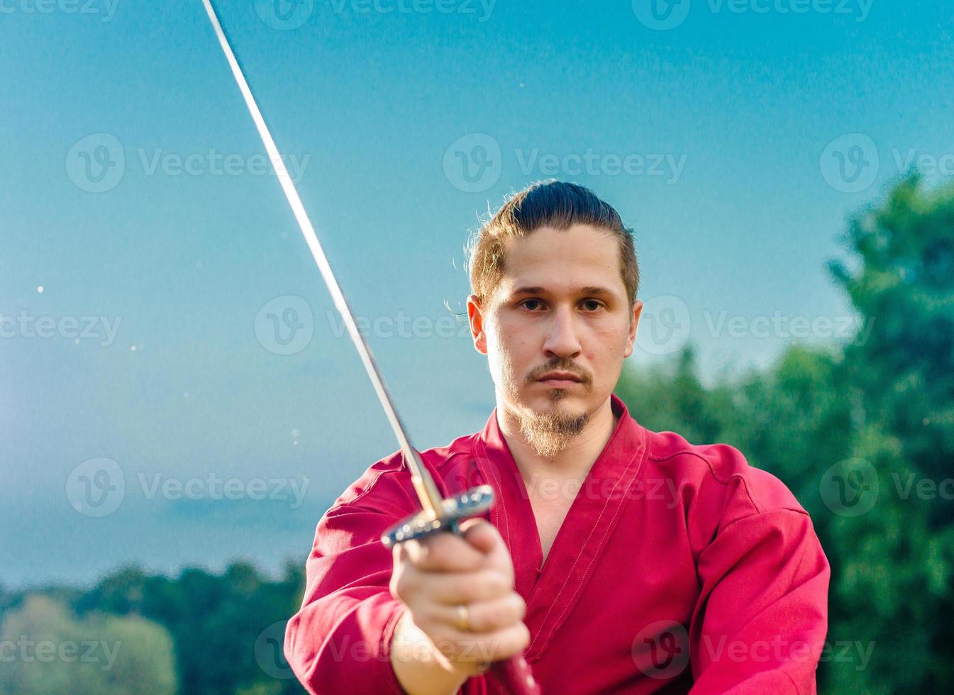 Mann in ethnischer Samurai japanischer Kleidungsuniform mit Katana-Schwert foto