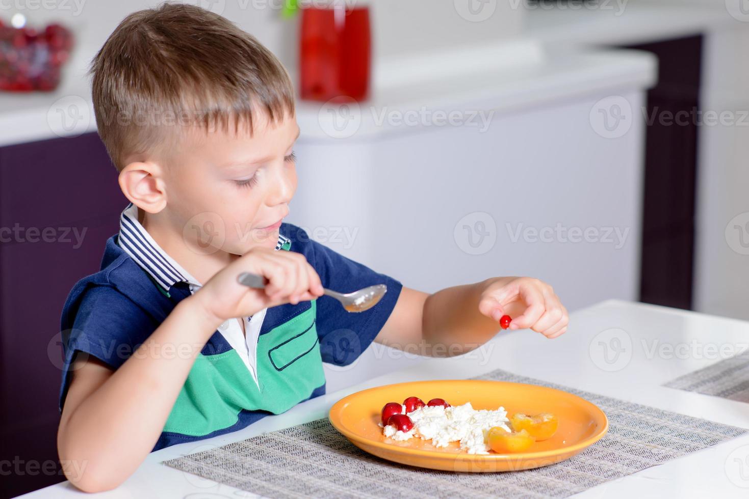 Junge, der Teller mit Käse und Obst isst foto