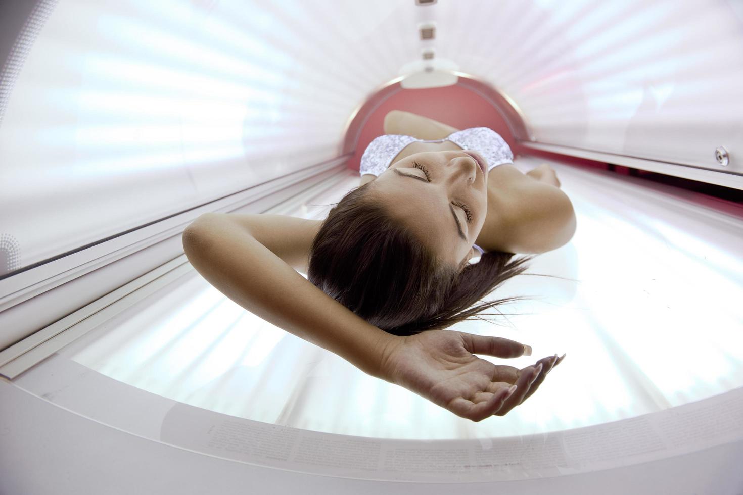 schöne junge Frau im Solarium bräunen foto