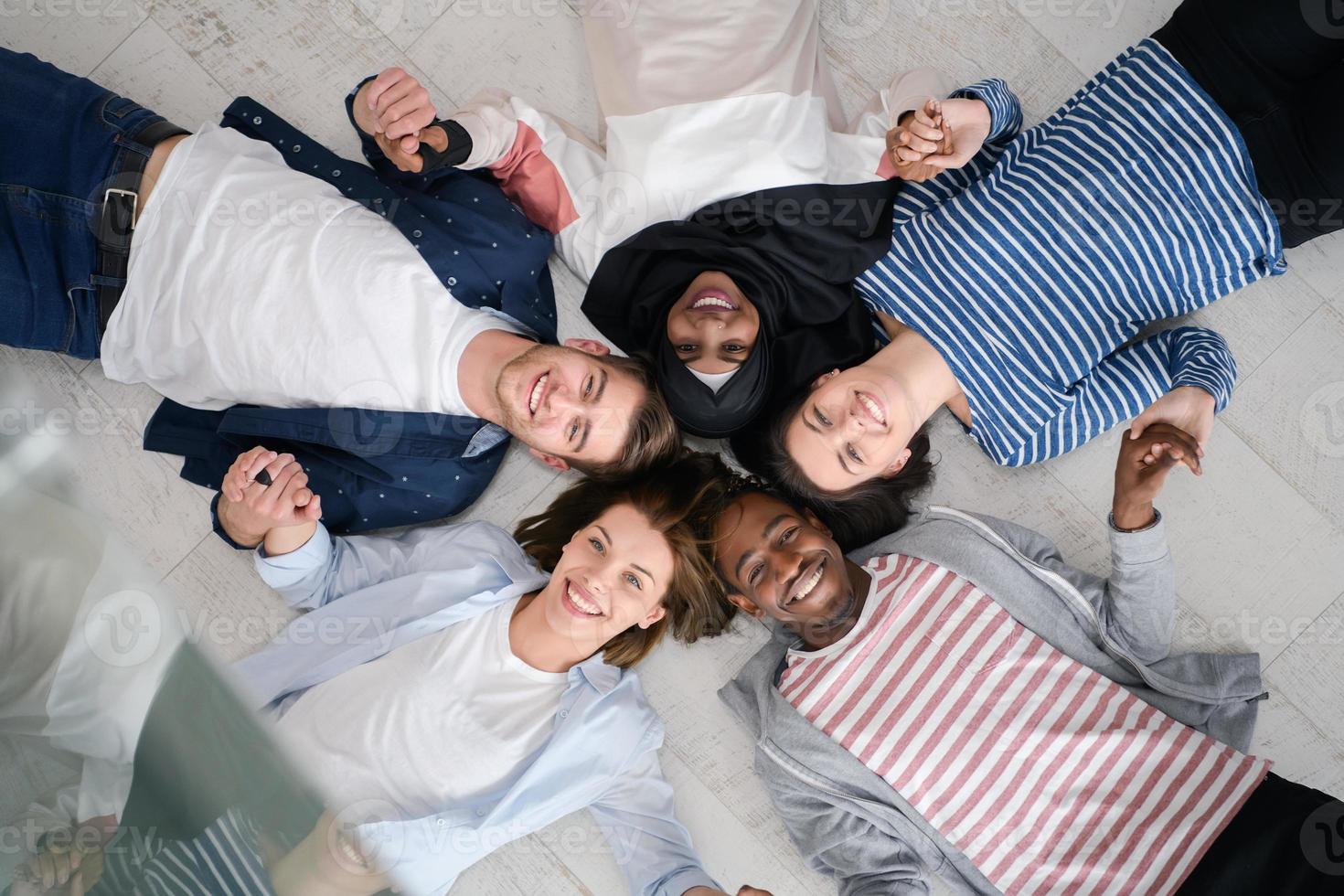 Draufsicht auf eine vielfältige Gruppe von Menschen, die auf dem Boden liegen und Zusammengehörigkeit symbolisieren foto