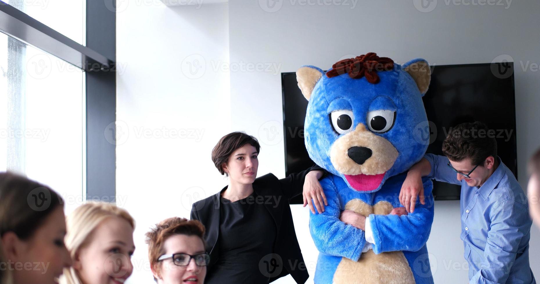 als bär verkleideter chef hat spaß mit geschäftsleuten im trendigen büro foto