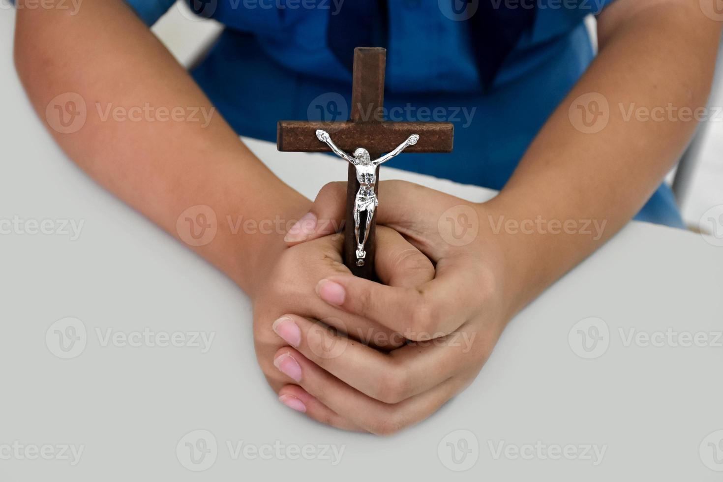 Holzkreuz mit einer Statue von Jesus, der von seinem Arm gekreuzigt wurde und die Hände des Gebets auf einem weißen Tisch in der Kirche hält, weicher und selektiver Fokus. foto