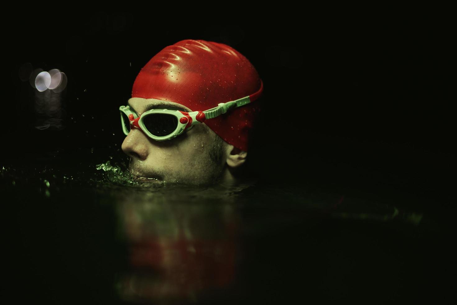 Authentischer Triathlet-Schwimmer, der während des harten Trainings im nächtlichen Neon-Gel-Licht eine Pause macht foto
