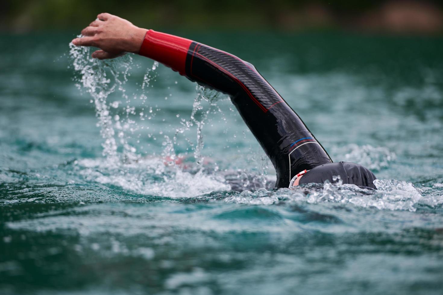 Triathlon-Athlet, der auf dem See schwimmt und einen Neoprenanzug trägt foto