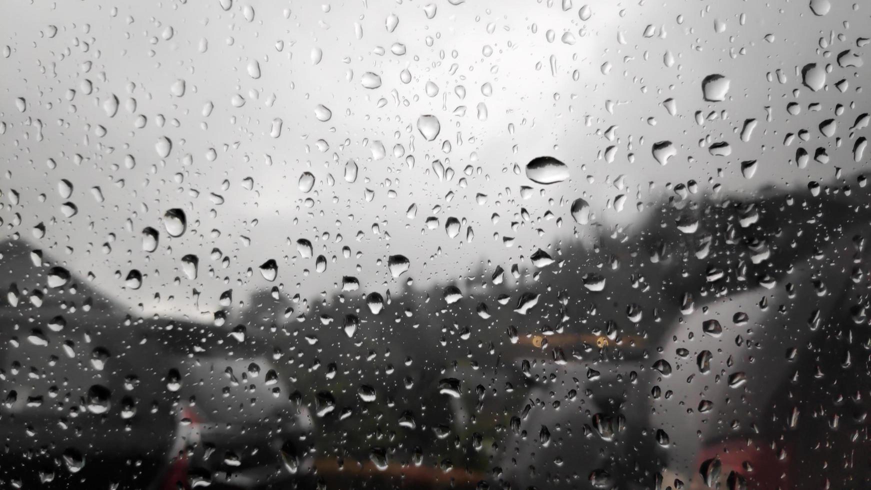 Regentropfen auf dem Fensterglas auf verschwommenem Stadthintergrund. Wassertropfen, Regenwetter foto