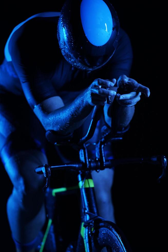 Triathlonsportler, der nachts schnell Fahrrad fährt foto