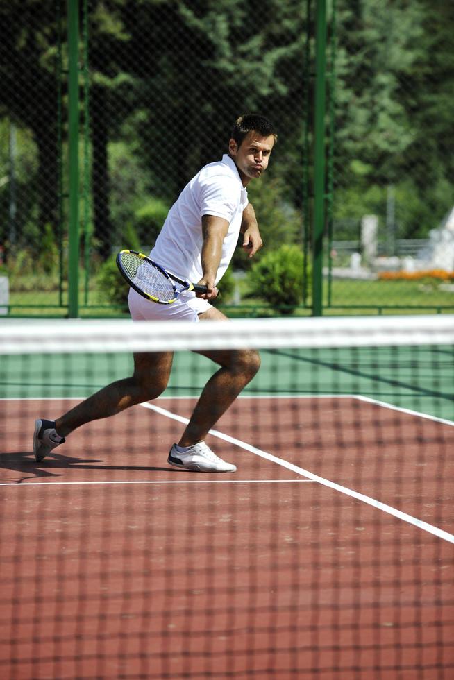 junger Mann spielt Tennis im Freien foto