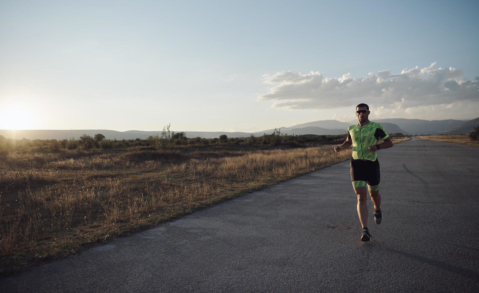 triathlonsportler, der beim morgendlichen training läuft foto