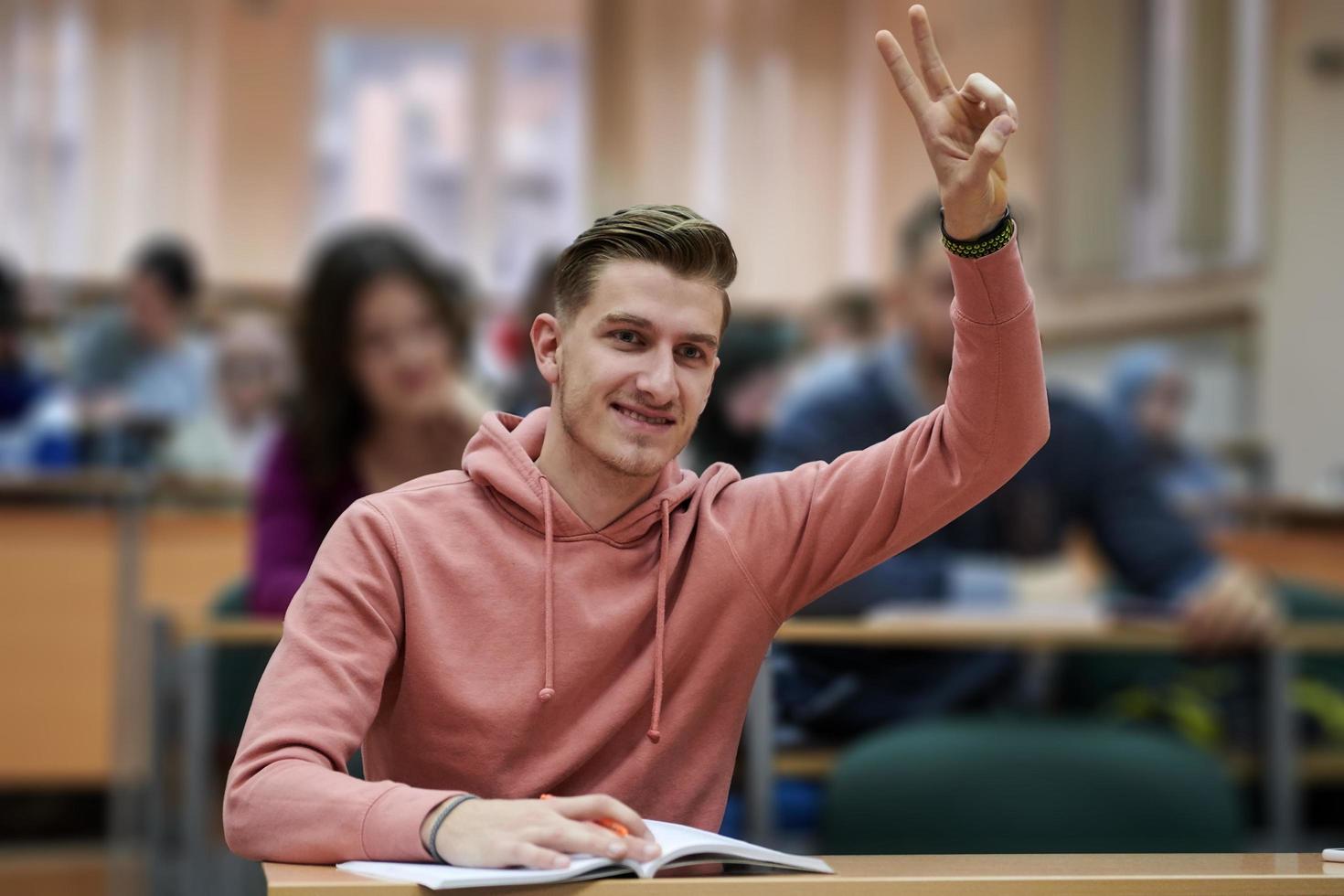 Der Student hebt die Hände und stellt im College eine Frage foto