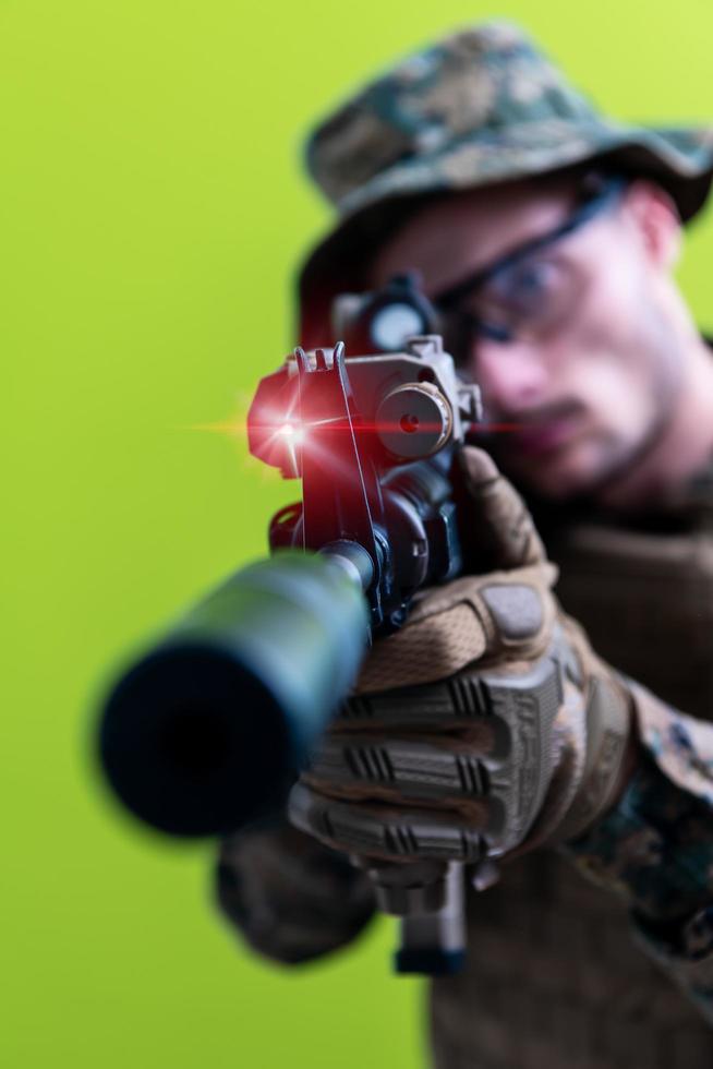 Soldat in Aktion mit dem Ziel Lasersichtoptik grüner Hintergrund foto