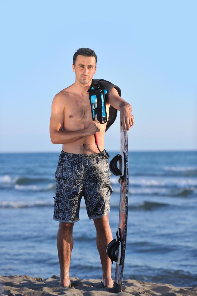 Porträt eines jungen Kitsurf-Mannes am Strand bei Sonnenuntergang foto