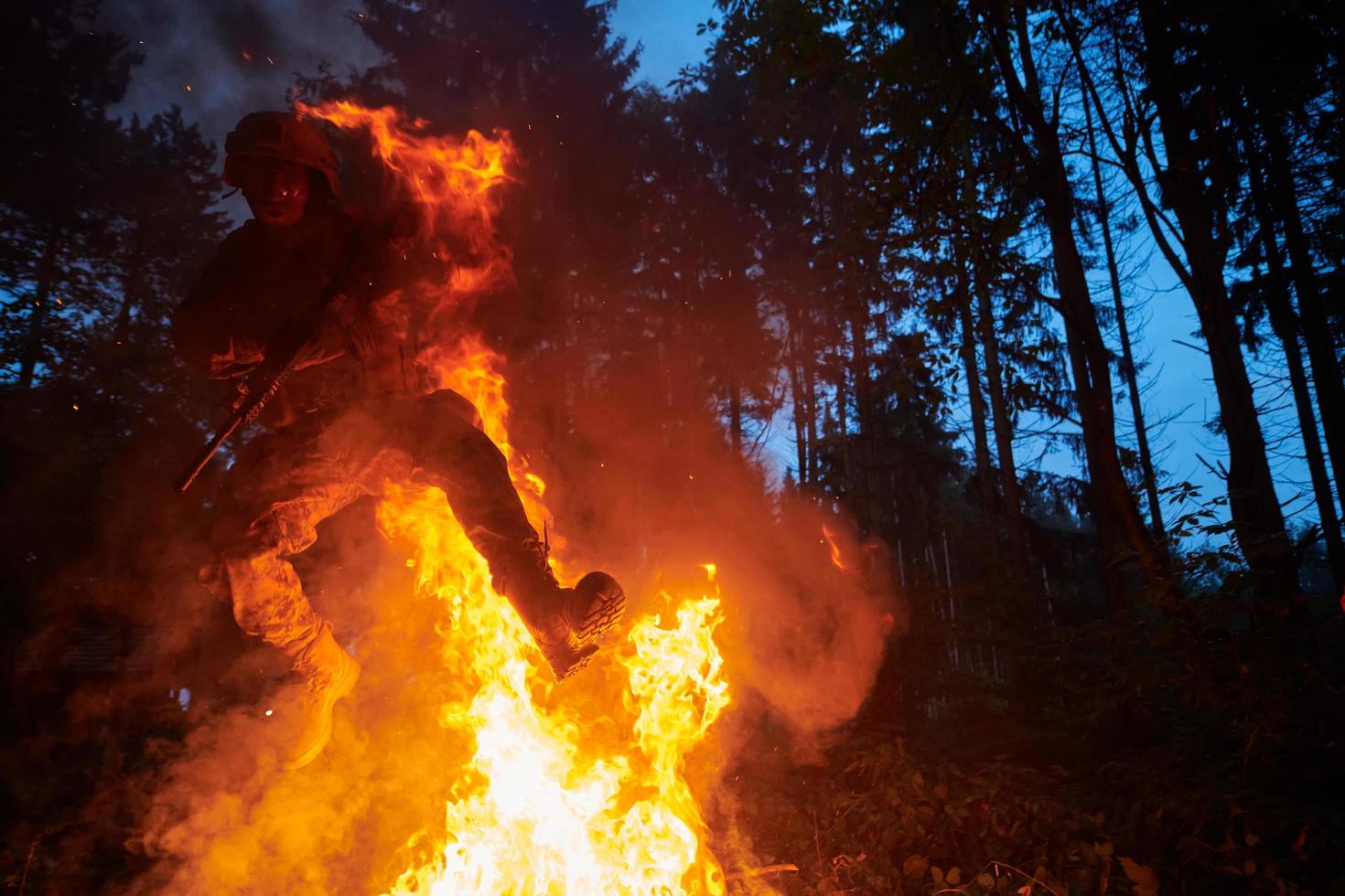 Soldat in Aktion bei Nacht beim Springen über Feuer foto