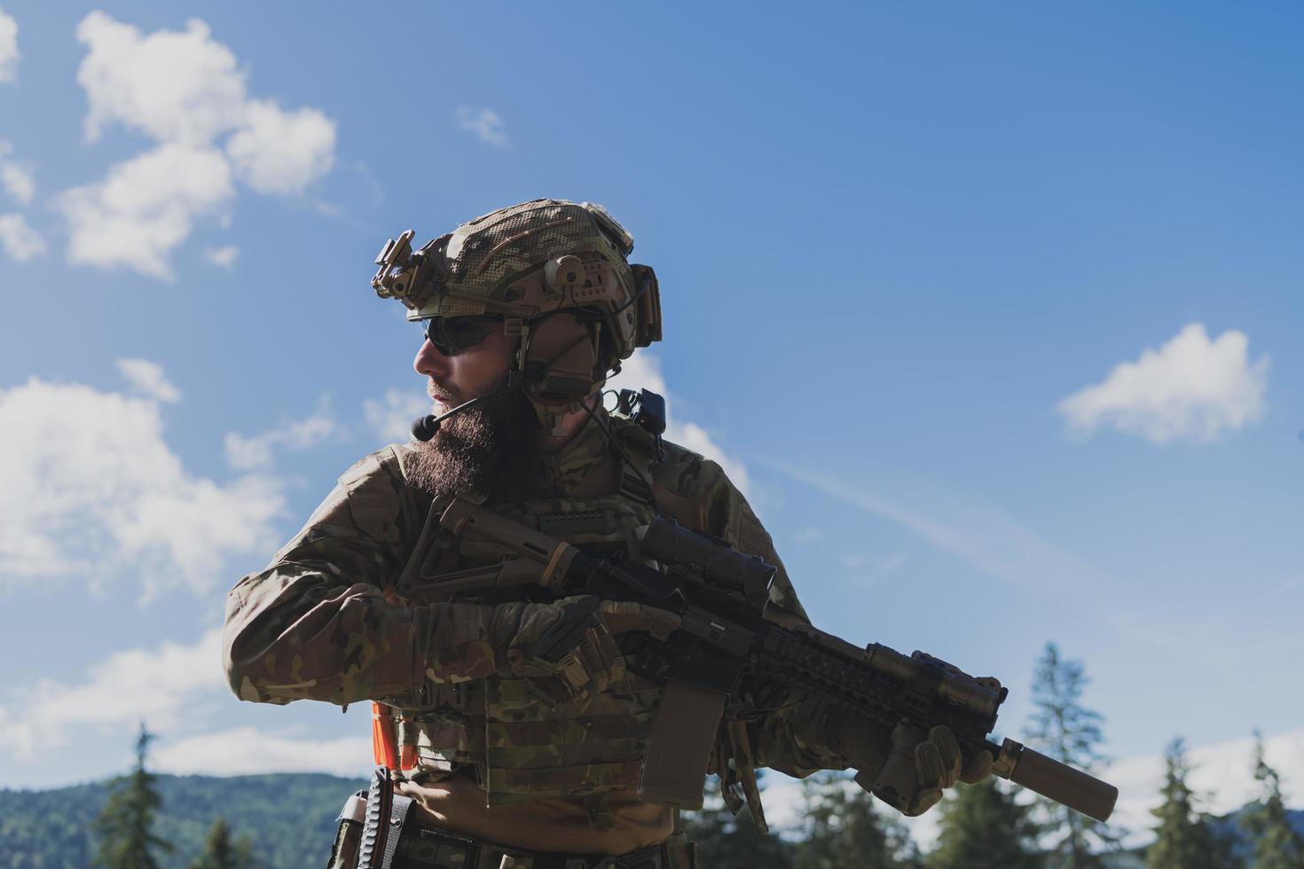 Kriegskonzept. Ein bärtiger Soldat in einer Spezialeinheit, der in einem Waldgebiet gegen einen Feind kämpft. selektiver Fokus foto