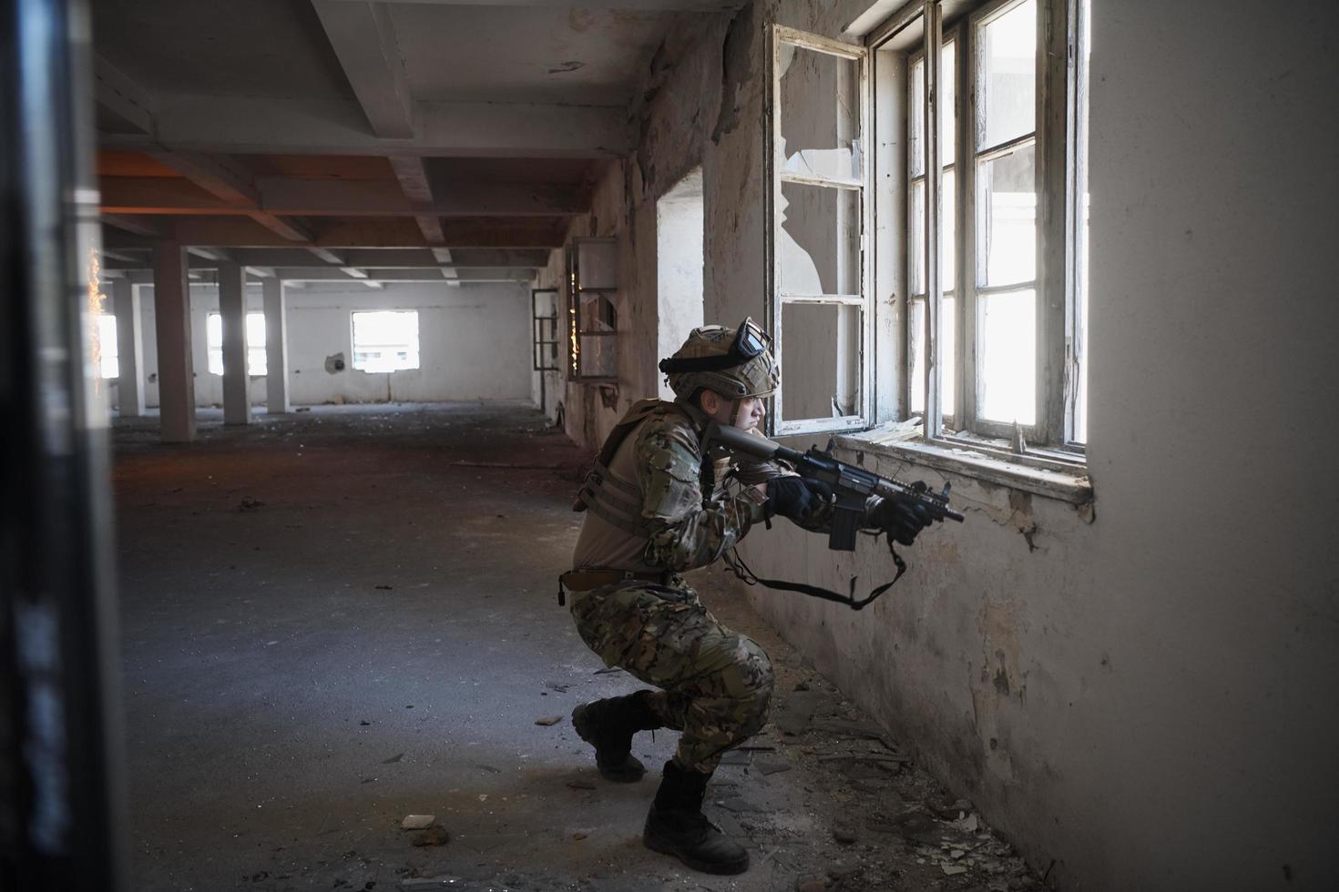 Soldat in Aktion in der Nähe des Fensterwechselmagazins und in Deckung gehen foto