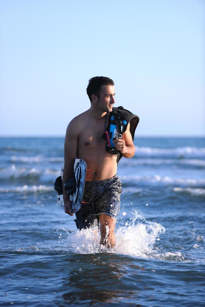 Porträt eines jungen Kitsurf-Mannes am Strand bei Sonnenuntergang foto