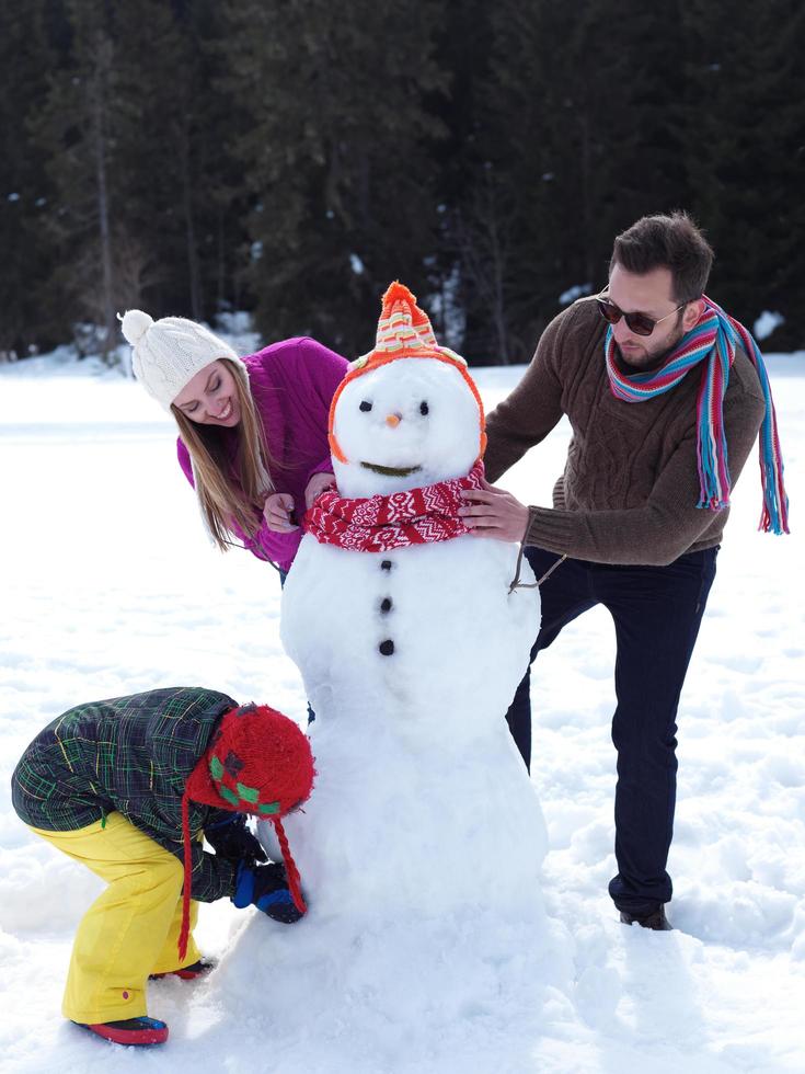 glückliche Familie, die Schneemann macht foto