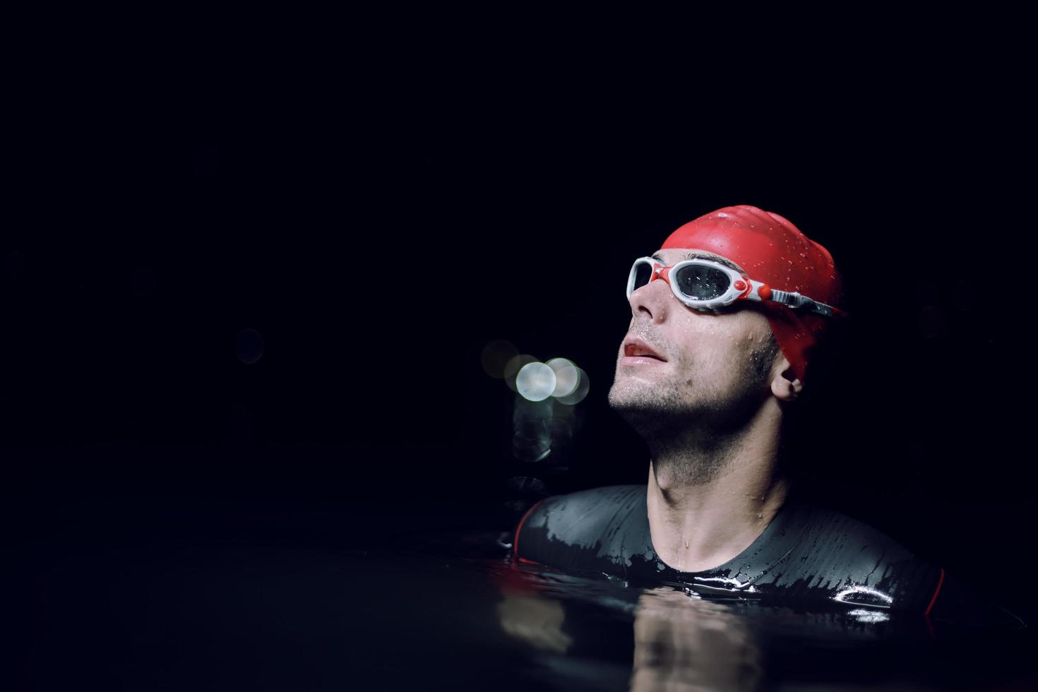 authentischer triathlet-schwimmer, der nachts während des harten trainings eine pause macht foto