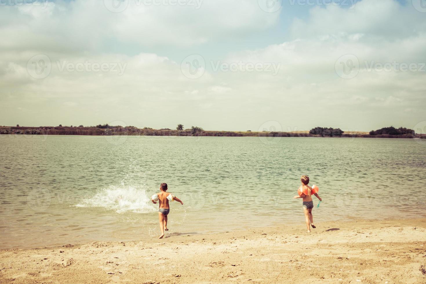 Rückansicht von Kindern, die Spaß haben und am Sommertag am Strand laufen. foto