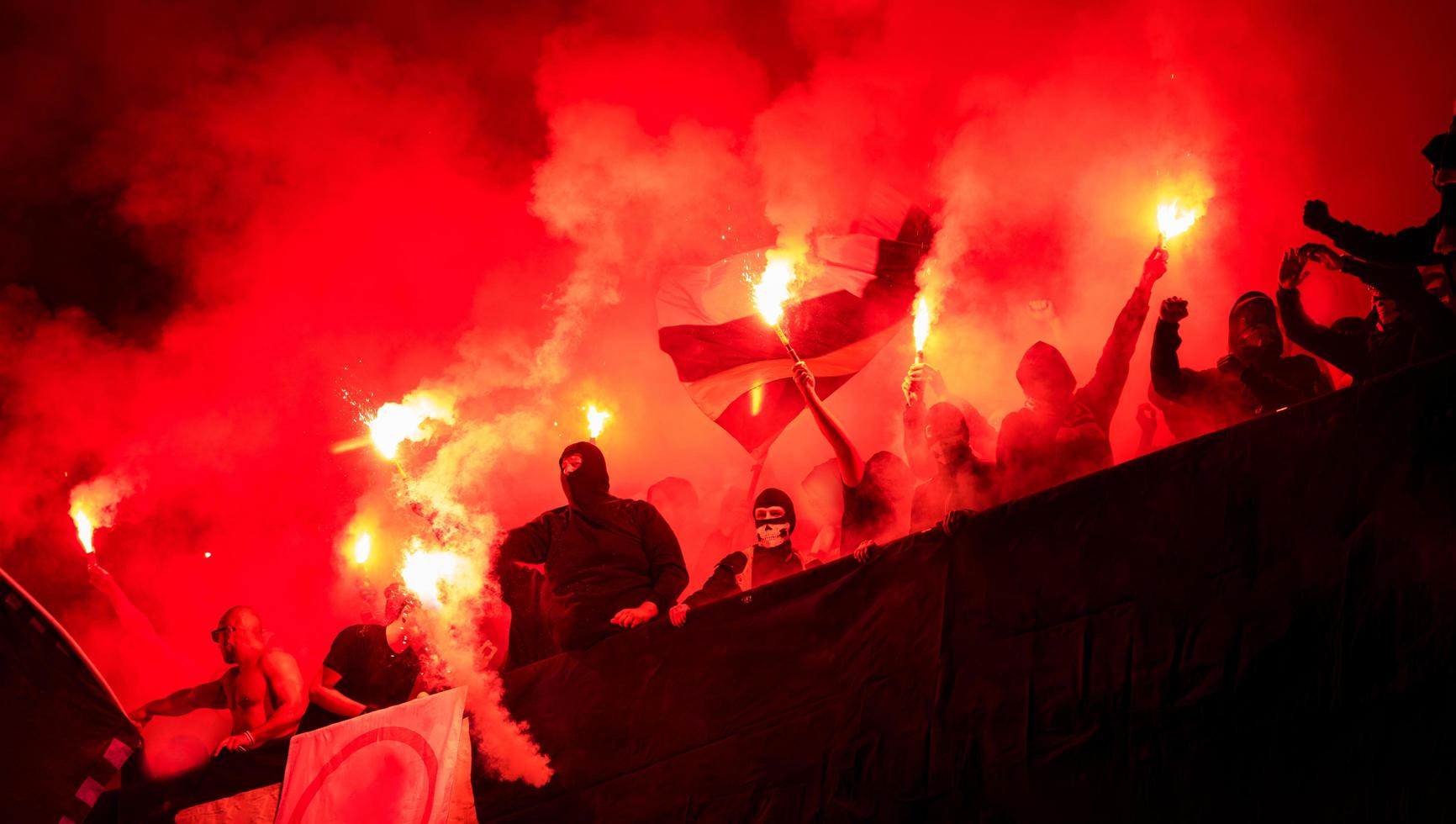 Fußball-Hooligans mit Maske, die Fackeln im Feuer halten foto