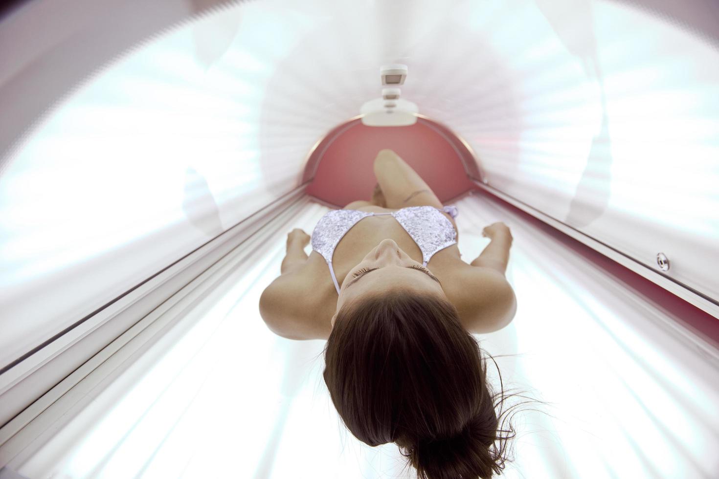 schöne junge Frau im Solarium bräunen foto